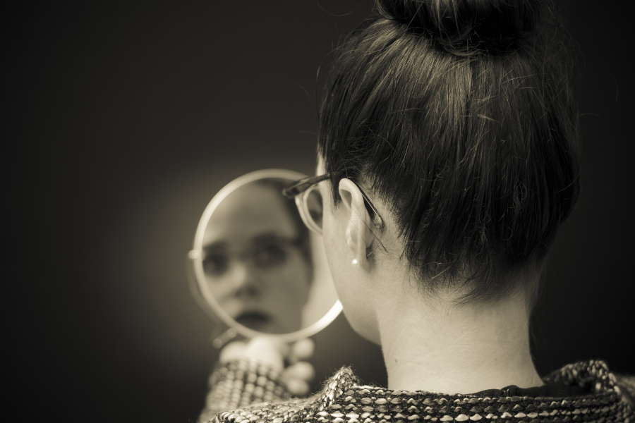 Una imagen en blanco y negro de una mujer joven mirándose al espejo.